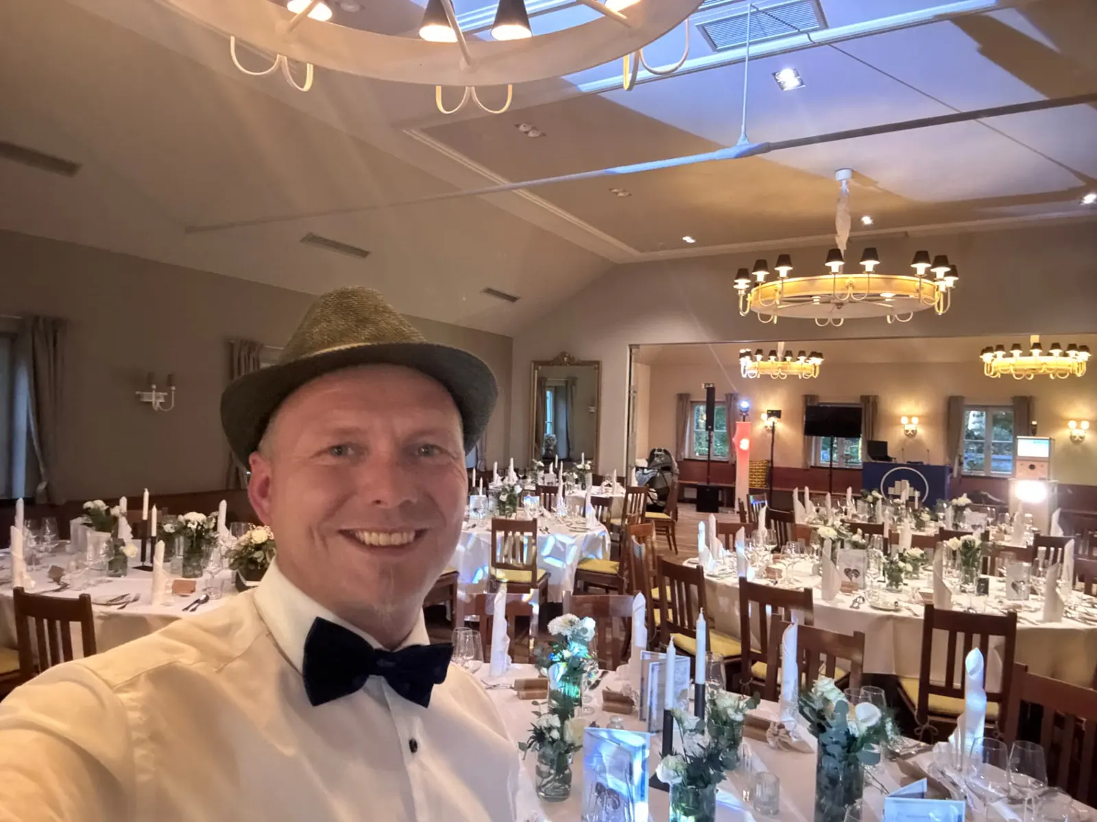 DJ Maik Spiering mit Hut und Fliege vor der Hochzeitsgesellschaft in der Hirschau